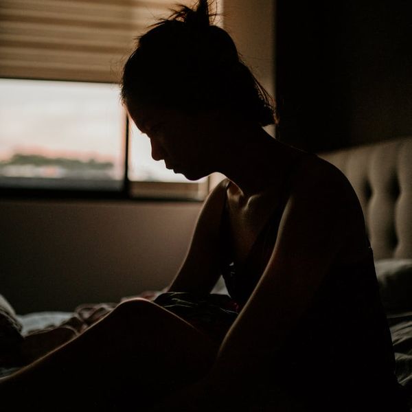 Silhouette of a person stretching during sunrise with cyan glow.